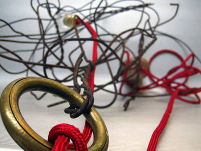 Esta lámpara se compone de un lío de alambre oxidado, la Fuente de luz es una bombilla bañada en oro suspendida con un hilo de color rojo